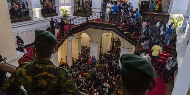 Army officers stand guard as people throng President Gotabaya Rajapaksa’s official residence for the second day after it was stormed in Colombo, Sri Lanka, on July 11.