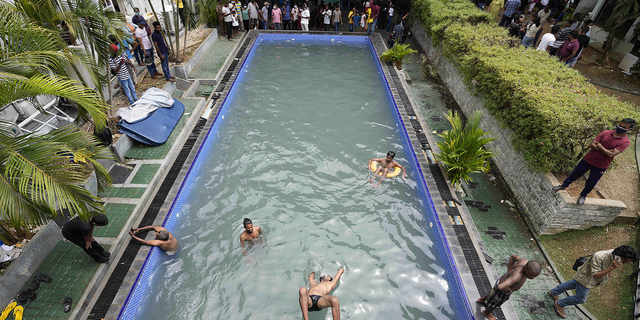 Protesters swim as onlookers wait at a swimming pool in president's official residence a day after it was stormed in Colombo, Sri Lanka, on July 10.