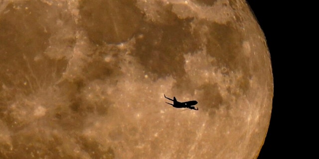 A plane passes in front of a full moon Wednesday, July 13, 2022, in Milwaukee. 