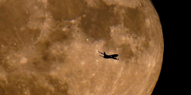 A plane passes in front of a full moon Wednesday, July 13, 2022, in Milwaukee.