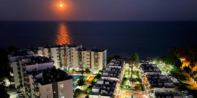 A supermoon rises over the Mediterranean Sea, in front of a residential compound, in the southern coastal city of Mersin, Turkey, Wednesdsay, July 13, 2022. 