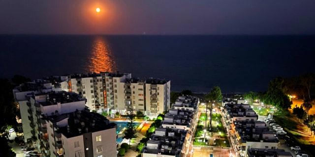 A supermoon rises over the Mediterranean Sea, in front of a residential compound, in the southern coastal city of Mersin, Turkey, Wednesdsay, July 13, 2022.