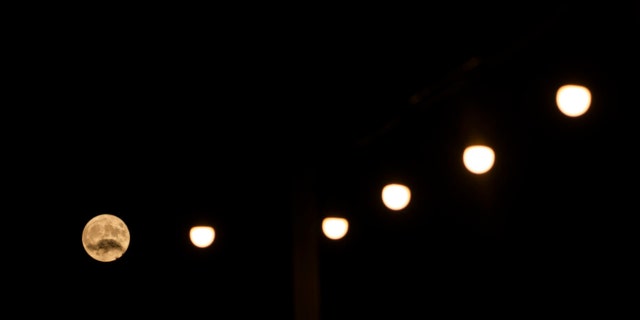 The Buck Supermoon rises behind lights near the town of Aegio, in the northern Peloponnese, Greece, on Wednesday, July 13, 2022.