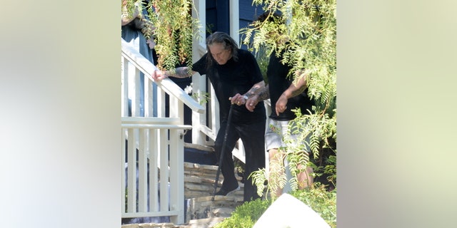 The Black Sabbath singer wore a pair of black and white sneakers, and walked a black cane with a shiny gold handle.