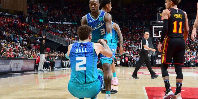 Terry Rozier #3 helps LaMelo Ball #2 of the Charlotte Hornets up during the game against the Atlanta Hawks during the 2022 Play-In Tournament on April 13, 2022 at State Farm Arena in Atlanta, Georgia.
