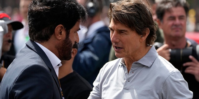 Tom Cruise, right, talks to an unidentified person on the grid before the British Formula One Grand Prix at the Silverstone circuit, in Silverstone, England, Sunday, July 3, 2022.