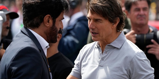 Tom Cruise, right, talks to an unidentified person on the grid before the British Formula One Grand Prix at the Silverstone circuit, in Silverstone, England, Sunday, July 3, 2022.