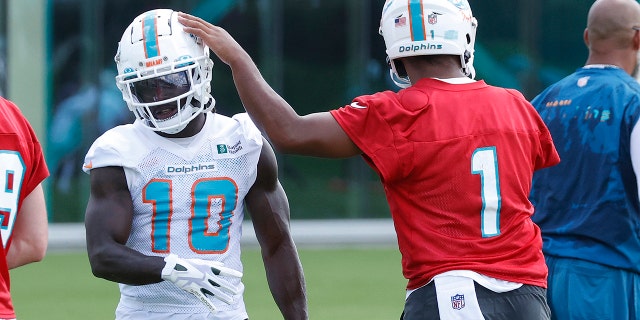 Tua Tagovailoa (1) taps the helmet of Tyreek Hill (10) between drills during the Miami Dolphins' mandatory minicamp at the Baptist Health Training Complex June 1, 2022, in Miami Gardens, Fla.