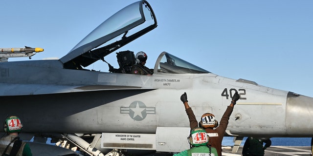 A crew member directs an F/A-18 Hornet fighter jet as it prepares to take off from the deck of the US Nimitz-class nuclear-powered aircraft carrier USS Harry S. Truman, during a NATO vigilance activity NEPTUNE SHIELD 2022 (NESH22) on eastern Mediterranean Sea on May 23, 2022.