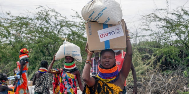 Locals residents carry a boxes and sacks of food distributed by the United States Agency for International Development (USAID), in Kachoda, Turkana area, northern Kenya, Saturday, July 23, 2022. Samantha Power, Administrator of the United States Agency for International Development (USAID) visited Kachoda Saturday with the intention to put measures in place that would help avert a hunger crisis in East Africa.
