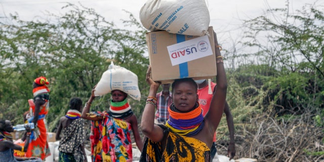 Locals residents carry a boxes and sacks of food distributed by the United States Agency for International Development (USAID), in Kachoda, Turkana area, northern Kenya, Saturday, July 23, 2022. Samantha Power, Administrator of the United States Agency for International Development (USAID) visited Kachoda Saturday with the intention to put measures in place that would help avert a hunger crisis in East Africa.