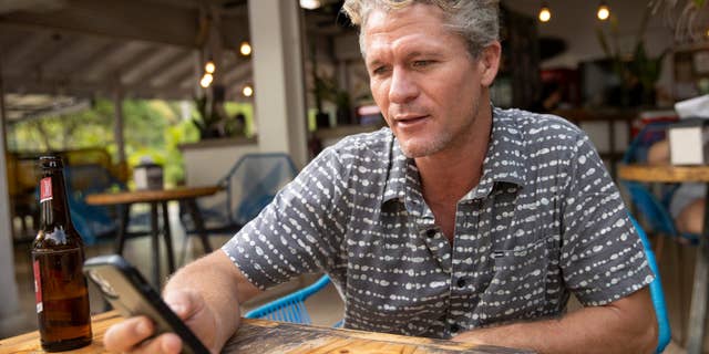 Teal Oceans Akerson looks at text messages from fugitive Kaitlin Armstrong in Santa Teresa, Costa Rica, July 8, 2022. Akerson said he went on four or five dates with Armstrong, who used an alias.