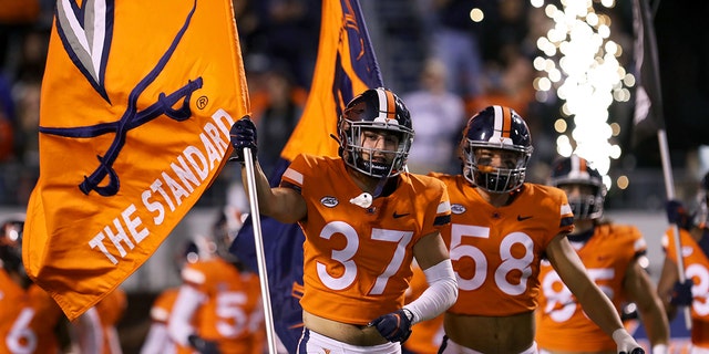 Darren Klein #37 leads the Virginia Cavaliers onto the field before a game against the Georgia Tech Yellow Jackets at Scott Stadium on October 23, 2021 in Charlottesville, Virginia.