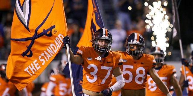 Darren Klein #37 leads the Virginia Cavaliers onto the field before a game against the Georgia Tech Yellow Jackets at Scott Stadium on October 23, 2021 in Charlottesville, Virginia.