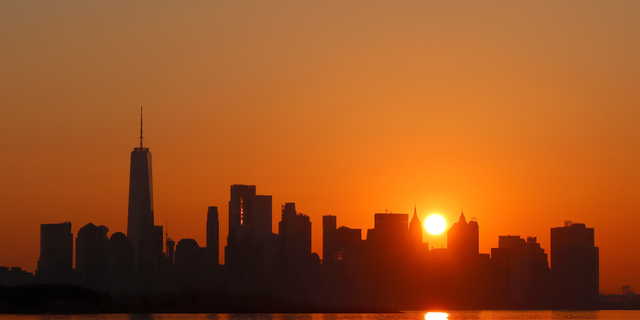 El sol sale detrás del bajo Manhattan y el One World Trade Center mientras continúa la ola de calor en la ciudad de Nueva York el 23 de julio de 2022, visto desde la ciudad de Jersey, Nueva Jersey. 