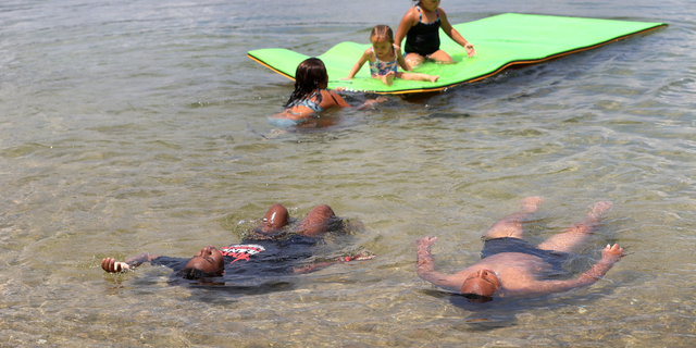 A family relaxes in the cool waters of Mashpee Pond on Cape Cod during a summer heat wave.