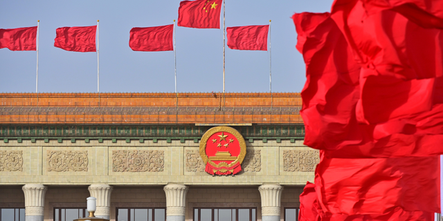 China's flag and other red flags flutter in front of the Great Hall of the People in Beijing, China.