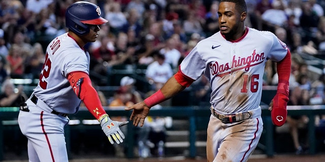 Washington Nationals' Victor Robles (16) is congratulated by Juan Soto after Robles scored against the Arizona Diamondbacks during the third inning of a game on Saturday, July 23, 2022, in Phoenix.