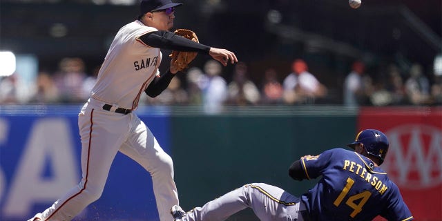 San Francisco Giants second baseman Wilmer Flores, left, throws to first base after forcing Milwaukee Brewers' Jace Peterson (14) out at second base on a double play hit into by Hunter Renfroe during the second inning of a baseball game in San Francisco, Sunday, July 17, 2022.