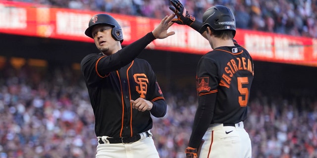 The San Francisco Giants' Wilmer Flores, left, is congratulated by Mike Yastrzemski after scoring against the Milwaukee Brewers during the eighth inning in San Francisco Saturday, July 16, 2022. 