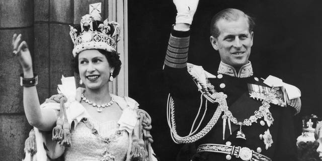 Queen Elizabeth II and the Duke of Edinburgh wave at the crowds from the balcony at Buckingham Palace after Elizabeth's coronation on June 2, 1953. 