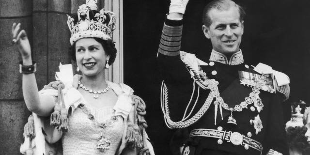 Queen Elizabeth II and the Duke of Edinburgh wave at the crowds from the balcony at Buckingham Palace after Elizabeth's coronation, June 2, 1953.