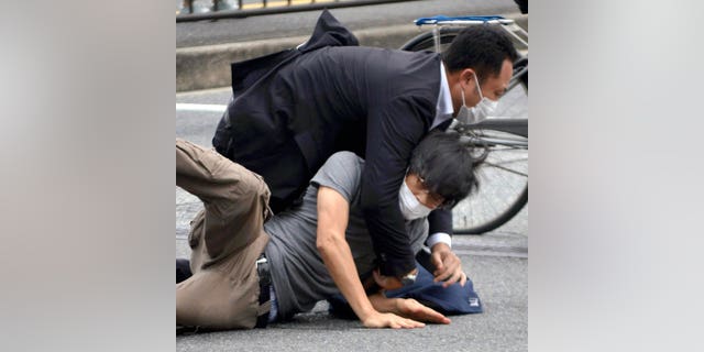 야마가미 테츠야(아래)가 2022년 7월 8일 금요일 서일본 나라현의 총격 현장 근처에 구금되어 있다.