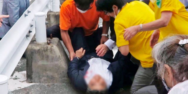 Japan’s former Prime Minister Shinzo Abe, center, falls on the ground in Nara, western Japan Friday, July 8, 2022. 