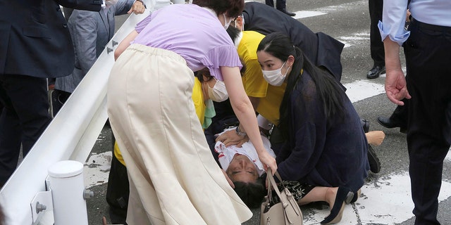 Japan’s former Prime Minister Shinzo Abe, center, falls on the ground in Nara, western Japan Friday, July 8, 2022.