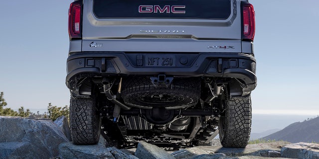 The 2023 GMC Sierra 1500 AT4X AEV Edition traveling off-road in the mountains. The AEV Edition features AEV branding throughout the vehicle as well as a black contrast inner tailgate.  Also included is a full-size spare 33-inch Goodyear Wrangler Territory MT tire.