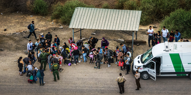 Aerial view of immigrants waiting to board a Border Patrol vehicle to be taken for processing, after crossing the border from Mexico on June 22, 2022 in Yuma, Arizona. 