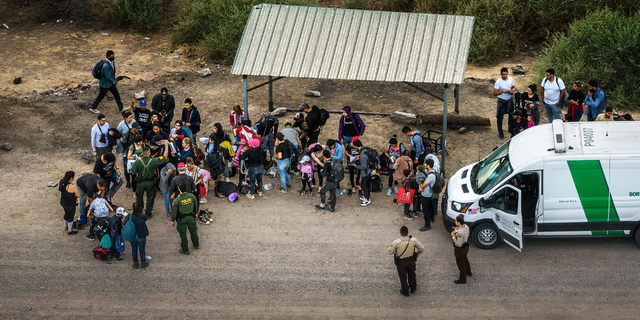 Aerial view of immigrants waiting to board a Border Patrol vehicle to be taken for processing, after crossing the border from Mexico on June 22, 2022 in Yuma, Arizona.