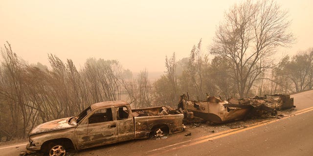 A burned pickup truck and a trailer in the middle of state Highway 96 were destroyed by the McKinney Fire in Klamath River, California, Saturday, July 30, 2022.