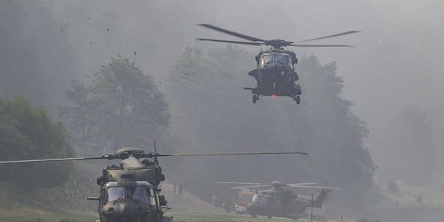 A Bundeswehr helicopter lands on the banks of the Elbe River to support firefighting efforts in the Saxon Switzerland National Park in Schmilka, Germany.