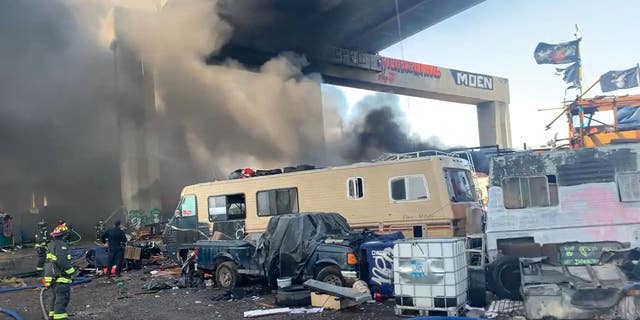 RV on fire with smoke under a bridge