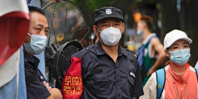 Security guards wearing face masks stand watch at the Nanluoguxiang, Beijing's popular tourist spot, Tuesday, July 19, 2022. 