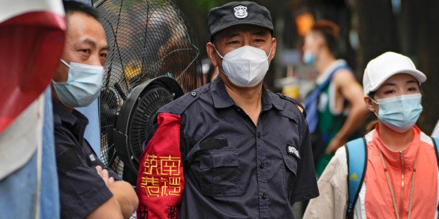 Security guards wearing face masks stand watch at the Nanluoguxiang, Beijing's popular tourist spot, Tuesday, July 19, 2022.
