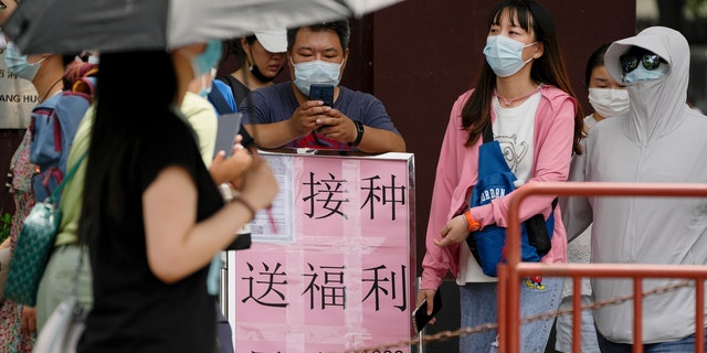 Los residentes con máscaras faciales pasan junto a un cartel que dice: 