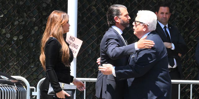 Don Trump Jr. outside funeral home, Kimberly Guilfoyle behind him.