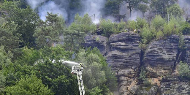 Firefighters use hoses to fight wildfires in Ceske Svycarsko, Czech Swiss National Park near Frensko, Czech Republic.