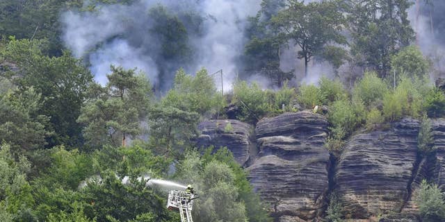 Firefighters use hoses to fight wildfires in Ceske Svycarsko, Czech Swiss National Park near Frensko, Czech Republic.