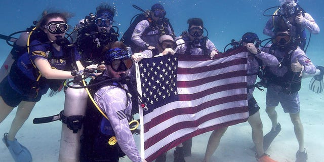 Army veterans, scientists and members of Force Blue and the Guy Harvey Ocean Foundation hold up the American flag underwater while on a mission to conserve coral reefs in Islamorada, Florida.
