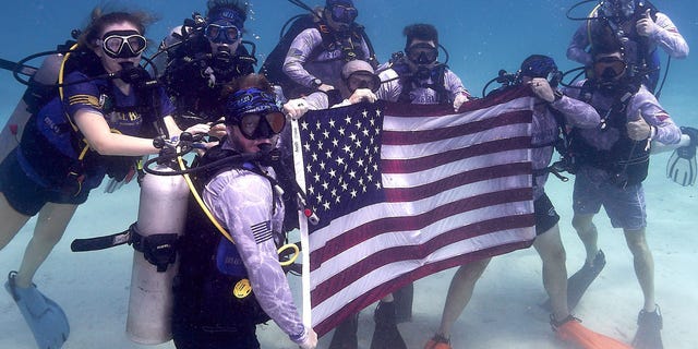 Army veterans, scientists and members of Force Blue and the Guy Harvey Ocean Foundation hold up the American flag underwater while on a mission to conserve coral reefs in Islamorada, Florida. 