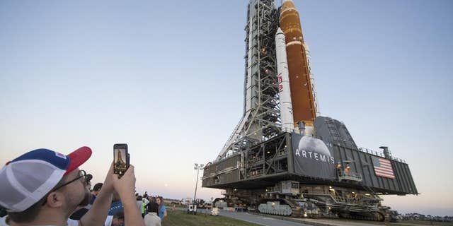 Invited guests and NASA employees take photos as NASA's Space Launch System (SLS) rocket with the Orion spacecraft aboard is rolled out of High Bay 3 of the Vehicle Assembly Building for the first time, at the Kennedy Space Center in Cape Canaveral, Fla.