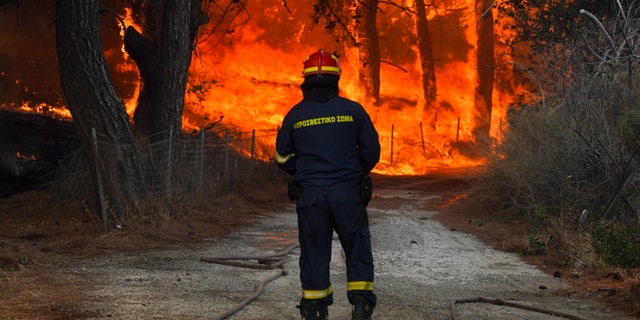 A firefighter tries to extinguishes a forest fire near the beach resort of Vatera, on the eastern Aegean island of Lesvos, Greece, Saturday, July 23, 2022. (AP Photo/Yorgos Karahalis)