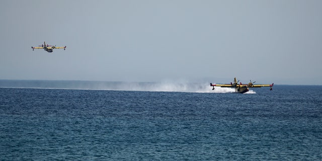 Firefighting aircrafts load water from the sea during a forest fire near the beach resort of Vatera, on the eastern Aegean island of Lesvos, on Saturday, July 23, 2022. Locals were evacuated on Saturday as a wildfire threatened properties near a beach in the southern part of the island, which is also a popular tourist attraction. (G3 Box News Photo/Panagiotis Balaskas)