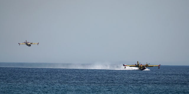 Firefighting aircrafts load water from the sea during a forest fire near the beach resort of Vatera, on the eastern Aegean island of Lesvos, on Saturday, July 23, 2022. Locals were evacuated on Saturday as a wildfire threatened properties near a beach in the southern part of the island, which is also a popular tourist attraction. (AP Photo/Panagiotis Balaskas)