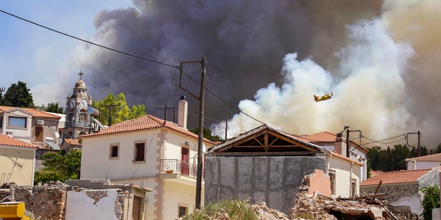 A firefighter aircraft drops water over a forest fire as smoke rises near Vrisa village, on the eastern Aegean island of Lesbos, on Sunday, July 24, 2022. A fire that broke Saturday morning on the Greek island of Lesbos prompted authorities to call for the evacuation of the Vatera resort on the south side of the island. (AP Photo/Panagiotis Balaskas)