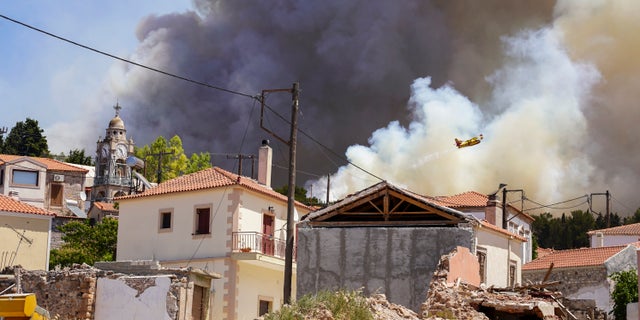 A firefighter aircraft drops water over a forest fire as smoke rises near Vrisa village, on the eastern Aegean island of Lesbos, on Sunday, July 24, 2022. A fire that broke Saturday morning on the Greek island of Lesbos prompted authorities to call for the evacuation of the Vatera resort on the south side of the island. (AP Photo/Panagiotis Balaskas)