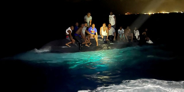 Survivors of a migrant boat that capsized are shown perching on the overturned vessel off the coast of New Providence island, Bahamas, July 24, 2022.